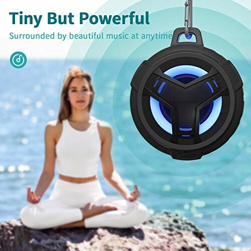 Person meditating by the sea with a portable speaker emitting sound waves.