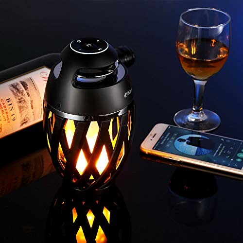 Decorative speaker with glowing light next to wine bottle, glass, and smartphone on table.